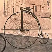 Énorme roue avant avec pédalier et selle, et petite roue arrière