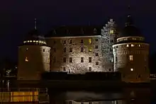 Château médiéval de nuit, éclairé par de faibles lumières.