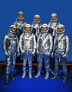 Sept astronautes en combinaison spatiale. Quatre à l'avant, trois à l'arrière.