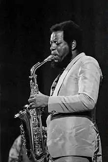 un Noir-Américain avec une petite barbe qui joue du saxophone.