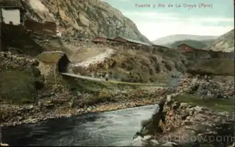 Carte postale représentant un pont enjambant une rivière et présentant deux maisons à ses extrémités.