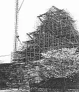 Photographie ancienne de la tour principale en reconstruction, entourée d'échafaudages.