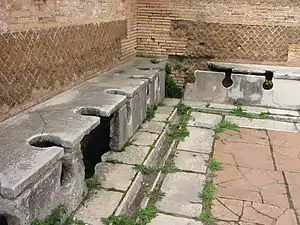 Photographie de toilettes publiques romaines (latrines), dans le port antique d'Ostie.