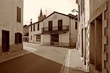 La Grande Rue avec en arrière-plan le clocher de l'église Saint-Barthélemy d'Oust.