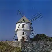 Photo d’un moulin à vent blanc, au toit couvert d’ardoises.