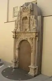 Photographie d'un'un portail d'église de style Renaissance s'insérant dans un bâtiment moderne en béton.
