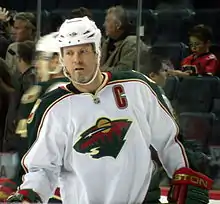 Photographie en couleur d'un joueur de hockey sur glace avec un maillot blanc et un casque de la même couleur