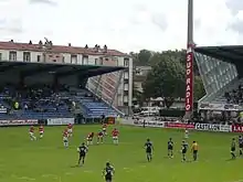 Des joueurs de rugby se tiennent à l'arrêt sur la pelouse d'un stade.