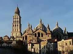 Photo prise en hiver représentant le côté sud ensoleillé de la cathédrale Saint-Front de couleur ocre et beige. À gauche, le haut clocher surplombé d'une lanterne architecturale. Sur sa droite, la nef que surmontent trois coupoles et dix lanternons.
