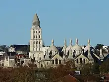 Photographie en couleurs des toits d'un grand bâtiment en pierre blanche, vu depuis le sud.
