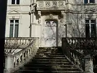 Un escalier pyramidal de douze marches donne sur la porte d'entrée de l'hôtel particulier à la façade blanche.