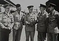 Cinq hommes en uniformes militaires clairs.