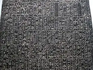 Photographie d'une portion de paroi de stèle, gravée d'une écriture cunéiforme pas encore caractéristique.