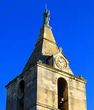 Le clocher avec une statue sommitale et une horloge.