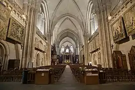  Photographie de la nef d'une cathédrale et de tapisseries accrochées.
