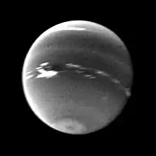Photo en noir et blanc de Neptune, la Grande Tache sombre est représentée et entourée de nuages très blancs.