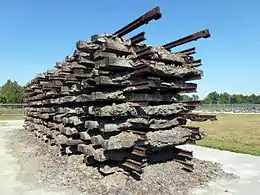 Photo couleur d'un empilement de bois et de traverses métalliques, formant un rectangle d'environ 2m de haut.