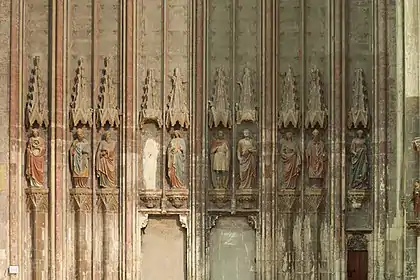 Dans dix niches, neuf statues (une niche vide) représentant quatre femmes et cinq hommes habillés à la romaine ou en costume médiéval.