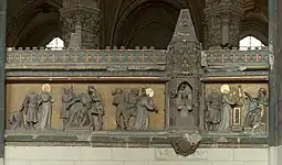 Bas-relief représentant, de gauche à droite, saint Quentin mené devant un homme sur un trône, saint Quentin avec les mains ligotées et enfermé dans une petite pièce, saint Quentin devant un homme sur un trône lui montrant des statuettes dorées.