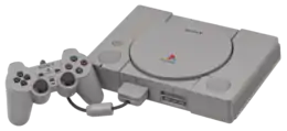Console PlayStation (boite grise connectée à une manette de jeu.