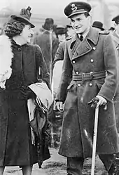 Photographie en noir et blanc d'un homme en uniforme se tenant à l'aide d'une canne.