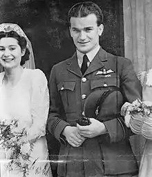 Photographie en noir et blanc d'un homme en uniforme à côté d'une femme en robe de marié.