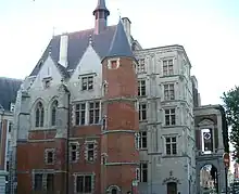 Vue de trois-quart de la façade d'un palais dont une partie est en brique rouge
