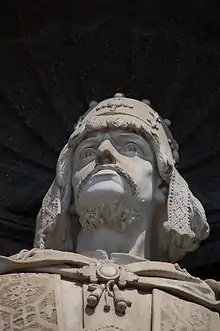 Photo détaillant la tête d'une statue, un homme moustachu et barbu portant une couronne