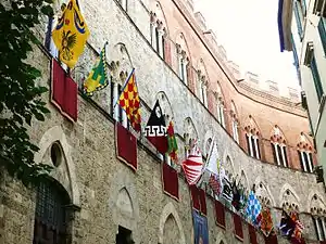 La façade arborant les drapeaux des contrade durant le palio.