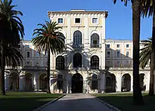 Photographie montrant la façade d'un palais, avec un corps central avancé, vu depuis le parc.
