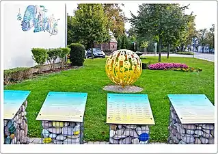 Photographie d'une boule de métal creuse fixée au sol dans un jardin public.