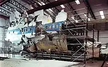 Photo montrant un échafaudage avec des débris de l'avion positionnés dessus pour reconstruire certaines parties.