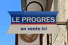 Panneau de commerce à la boulangerie du bourg annonçant la vente du journal de Le Progrès.