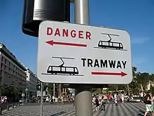 Image représentant un panneau d’avertissement de passage du tramway avec la mention « DANGER TRAMWAY » accroché sur un poteau.