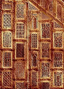 Photographie de plusieurs panneaux du minbar. Ces panneaux rectangulaires en bois de teck se distinguent par la diversité des motifs sculptés.
