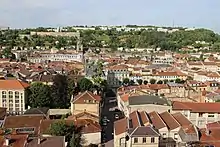 Photographie des toits de la ville au premier plan et des immeubles en arrière-plan.