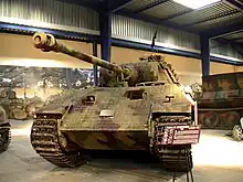 Photographie prise dans un musée et montrant de face un char Panther A peint en camouflage et couvert d’un revêtement granuleux.