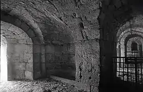 Photographie en noir et blanc d'un passage voûté en maçonnerie de grand appareil.