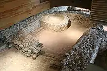 vue en surplomb des murs d'une pièce terminée par une abside et renferment un bassin en maçonnerie.