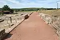 Vue d'une allée avec de part et d'autres des vestiges de bâtiments.