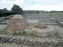 Vue de deux fours dont l'un, à gauche, a été reconstitué. À l'arrière-plan vue sur les ruines et sur la gauche plusieurs couvertures modernes destinées à protéger les vestiges.