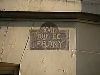 Plaque de rue (non réglementaire) de la rue de Prony, à l’angle de la rue Henri-Rochefort.