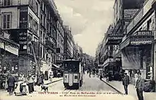 Carte postale de la rue de Belleville à Paris, traversée par un tramway funiculaire, où l'on observe diverses boutiques comme une boucherie et un théâtre populaire.