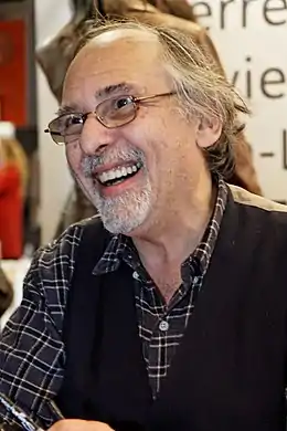 photo en couleur d'un homme souriant portant des lunettes