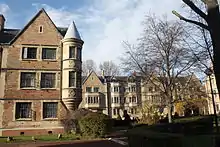 Deux bâtiment ancien de briques de 2 étages avec une tourelle avec un jardin au premier plan, en hiver