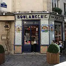 Boulangerie-pâtisserie au coin de la rue des Rosiers avec une devanture en mosaïques.