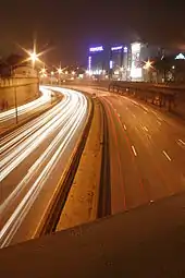 Vue du périphérique de nuit. Les phares des voitures laissent des trainées rouges à droite et blanche à gauche