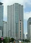 Ground-level view of a white, orange and green rectangular high-rise; its balconies form horizontal stripes up the height of the tower