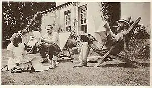 quatre personnes lisent dans un jardin, devant une maison