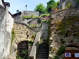 Photographie représentant le bas de la rue Chauchat construite en escaliers et collée contre une muraille de la quatrième enceinte.